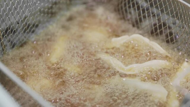 Gyoza dumpling fried cooking for food in deep fryer with hot cooking oil in kitchen of restaurant as Chinese, Japanese, Asian food style