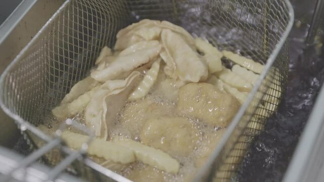 Gyoza dumpling fried cooking for food in deep fryer with hot cooking oil in kitchen of restaurant as Chinese, Japanese, Asian food style