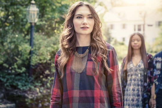 Young woman walking outdoors with people in background