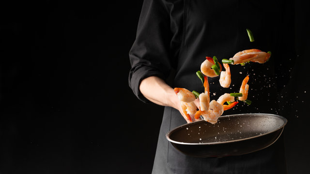 Seafood, Professional cook prepares shrimps with sprigg beans. Cooking seafood, healthy vegetarian food and food on a dark background. Horizontal view. Eastern kitchen