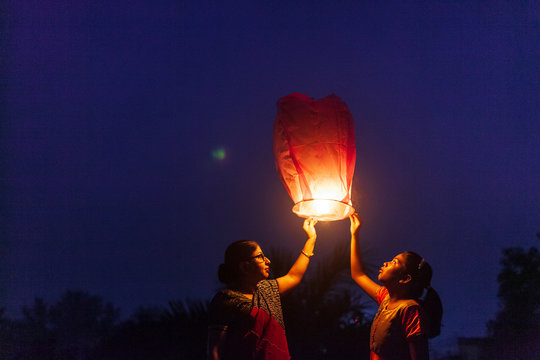 Little Girl And Her Mother Releasing Sky Lantern To The Sky At Twilight