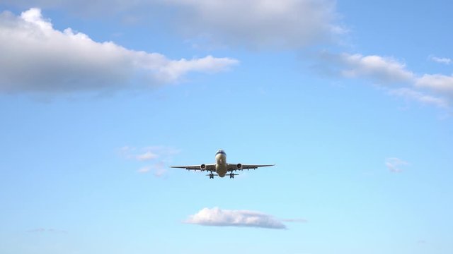 Modern large plane flies in the sky. Beautiful blue sky and white clouds in the background. The aircraft flies overhead. Airplane takes off or landing. Ultra HD footage. 4K