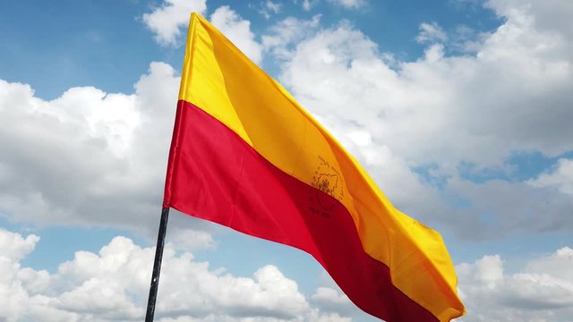 Close up of the official flag of the South Indian state of Karnataka flying against the sky and clouds in the background