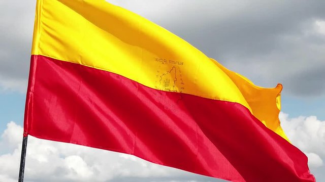 Close up of the official flag of the South Indian state of Karnataka flying against the sky and clouds in the background