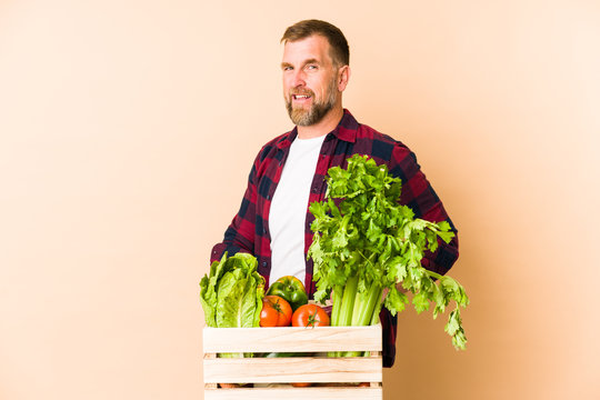 Farmer senior man isolated on beige background looks aside smiling, cheerful and pleasant.