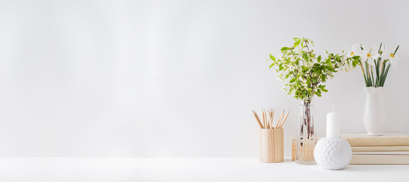 Home office, interior for bloggers workplace with white daffodils in a vase, office supplies on a light background