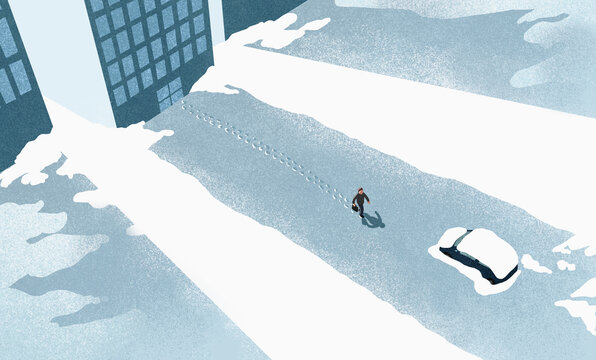 High angle view of man walking on snow covered road in city