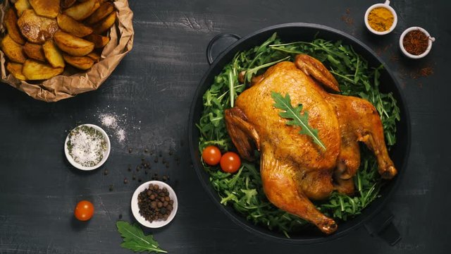 Roasted whole chicken or turkey served in iron pan Placed on black background Top view.