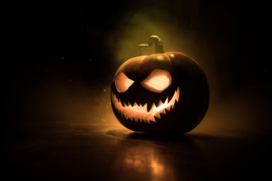 Halloween pumpkin smile and scary eyes for party night. Close up view of scary Halloween pumpkin with eyes glowing inside at black background