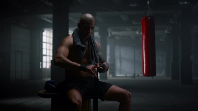 Boxer wrapping hands in boxing tapes. Focused sportsman using punching wraps 