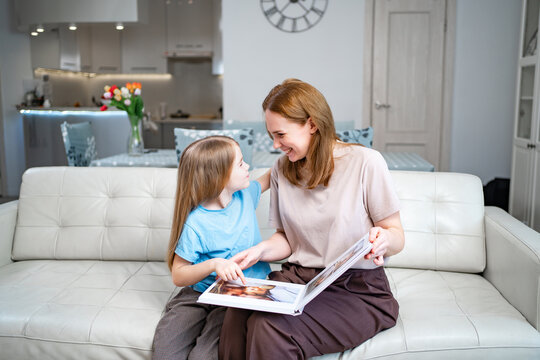 mother and daughter looking a book with photos from a family photo shoot