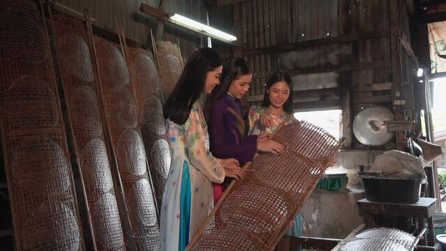 Three Beautiful woman made vietnamese  Rice paper is drying on the wooden pattern. 