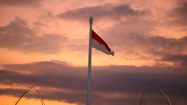 Indonesian flag flying on a high pole against a dramatic evening sky