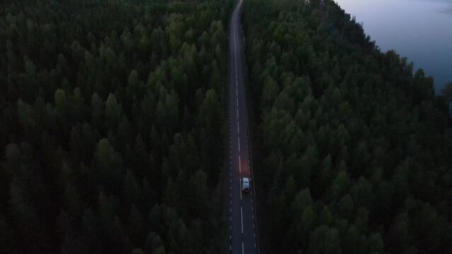 Aerial footage of a car driving alone through a forest at night in Norway