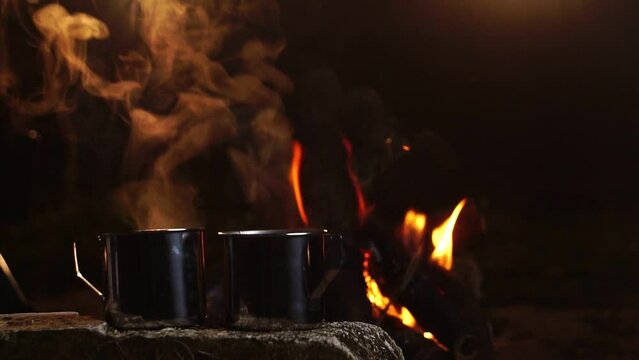 Seniors camping at night, resting on his winter vacation, a mug of warm water, around a campfire