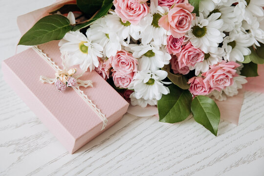 Beautiful bouquet of rose and chrysanthemums flowers and pink gift box on white table background. Gift for holiday, birthday, Wedding, Mother's Day, Valentine's day, Women's Day. Floral arrangement.