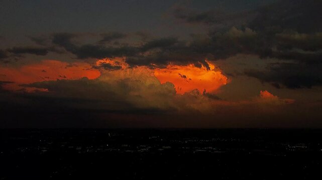 Time lapse of clouds in the bright orange sky over a town in the evening