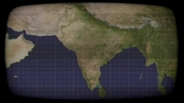 Deliberate distortion: an old color cathode-ray tube (CRT) TV monitor displaying a static satellite view of India. Themes: surveillance, global communications, classic spy story.
