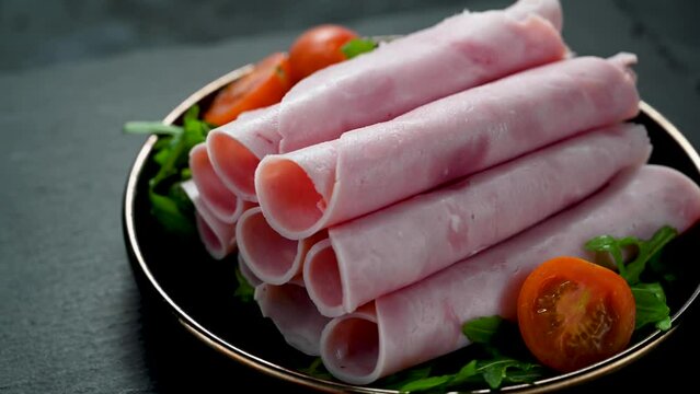 Delicious turkey ham slices in a black plate, over dark background