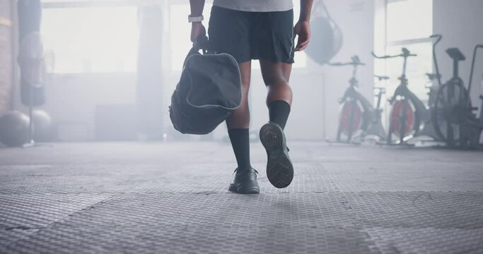 Person, athlete and walking with bag in gym for boxing challenge for competition, physical activity or wellness. Legs, shoes and muscle in training for fight workout or exercise, confident or health