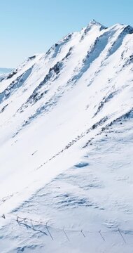 Aerial view of snow mountain range landscape in Sichuan China under blue sky with winding road and sea of clouds in the background 4k winter drone footage