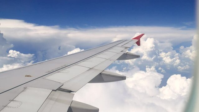 footage of close-up airplane window at empty passenger seat in cabin of the aircraft zoom out to the plane wing with white clouds floating in the sky at window view 