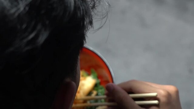 Close-up of a man's hand stirring chicken noodles with seasoningClose-up of a man eating chicken noodlesClose-up of a man eating chicken noodles