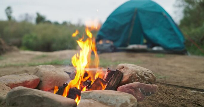 Fire, nature and camping wood with tent with heat and flames in the outdoor park. Adventure, field and holiday in a campsite with smoke, burning and pit for cooking on ground with grass at morning