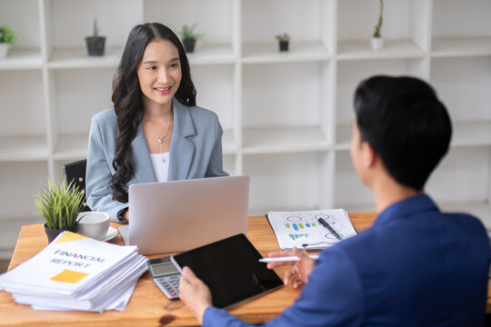 A young businessman and a female Asian accountant are discussing financial accounting and business planning together in the office.