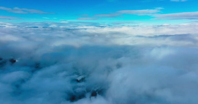 Aerial view of dense clouds and blue sky over snowy field on a sunny bright day