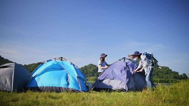 Travellers camping family under set up camp site Pulls and sticks a metal tent peg into the ground is holiday activity with mountain nature lifestyle.