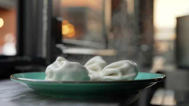 Appetizing hot khinkalia on the street. Khinkali are standing on the street, cooling down. Georgian cuisine, khinkali on a plate, on the street in the evening.