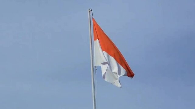 The red and white Indonesian flag flies in the blue sky