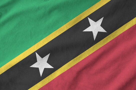 Saint Kitts and Nevis flag depicted on folded wavy fabric of old cloth close up