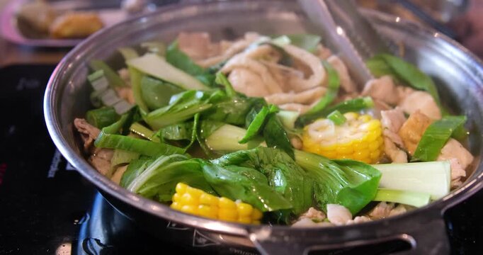 lid of a bubbling pot with broth boiling beneath, on a modern induction stove in a cozy kitchen. AI generative