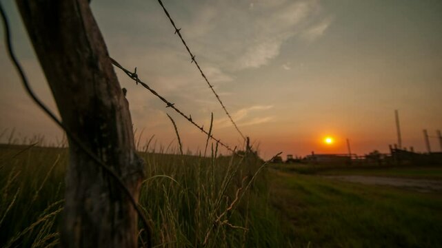 closeup footage of a sundown beyond the barbed wire