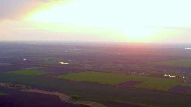 Aerial footage of a sunset over sprawling fields, captured by a drone, showcasing vibrant colors in the sky.