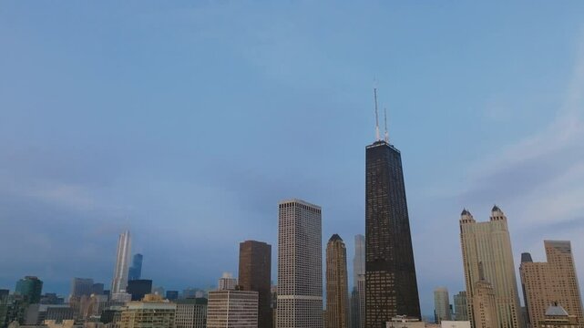 Aerial footage slowly panning down revealing the morning sky and the skyscrapers of downtown Chicago.