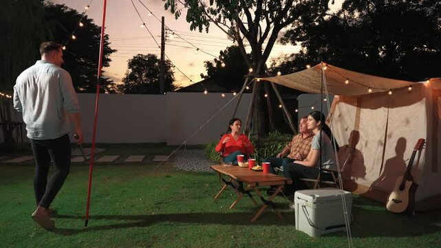 Family all together camp in garden, Father serve grilled food for family member. Outdoor camping activity to relax with nature and spend time with young generation cross generation gap. Divergence.