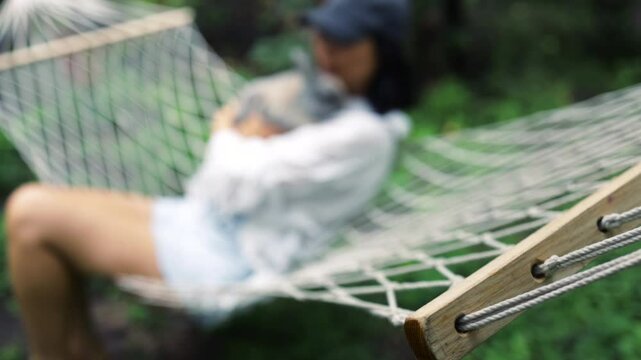 Asian girl lies on hammock in summer garden with Easter bunny. 