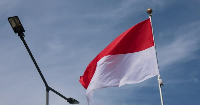 Indonesian flag, red and white flag, national symbol of Indonesia. Indonesian flag waving in blue sky. Independence Day of the Republic of Indonesia. Red and white flag, close-up. Great for news.