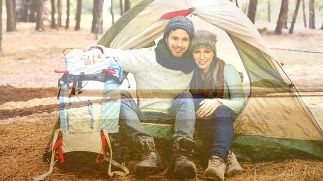 Camping couple sitting in tent with backpack over scenic landscape