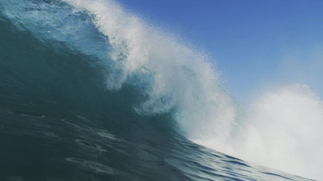 Slow-motion shot of a wave crashing with great intensity, filmed from inside the water at sunrise, showcasing the wave's raw power and motion