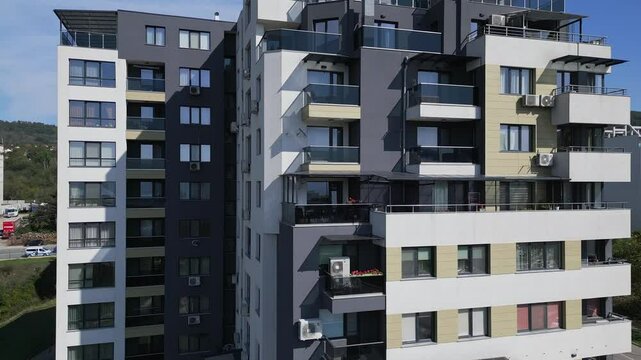 Aerial video of a modern apartment building with balconies and large windows, showcasing urban living. The footage captures clean architectural design and residential comfort in a city setting