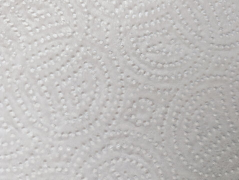 Close-up macro view of white embossed kitchen paper towel texture details with circular patterns design. Soft textured absorbent material for households cleaning and wiping surfaces efficiently. 