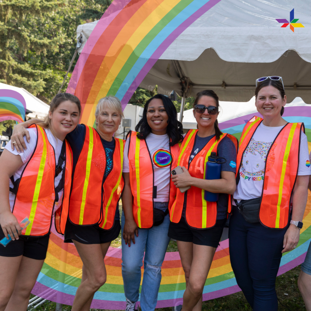 5 women in front of a tent outside wearing high visibility vests.