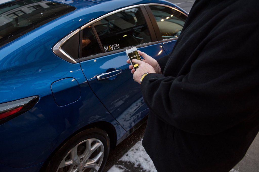 A person outside of a GM car uses app for subscription services