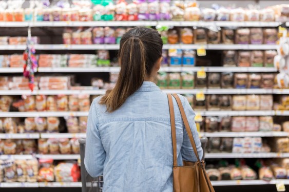 Woman facing shelves of bread in a grocery