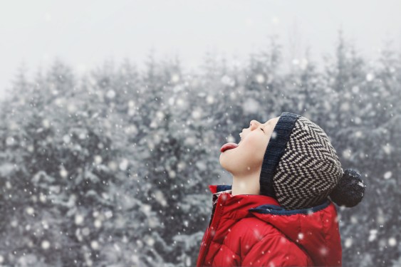 Little kid catching snowflakes with his tongue