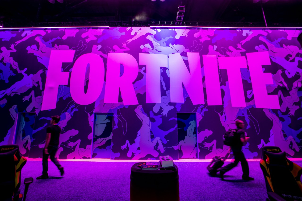 Attendees walk past signage for Epic Games Inc.'s Fortnite